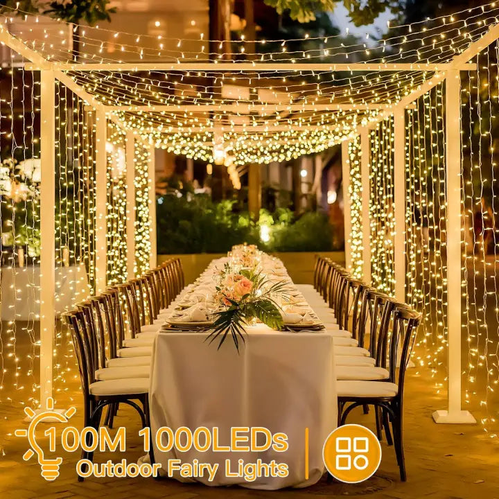 Decorative outdoor fairy lights draped over a canopy, table set for dinner, and floral centerpiece.
